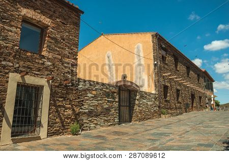 Street With Rustic Houses And Stone Walls With Plants