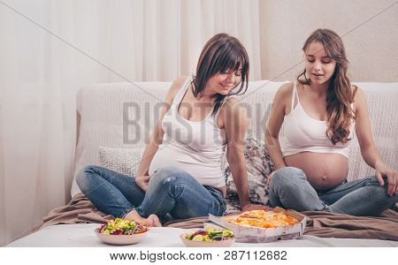 Two Pregnant Women Eating Pizza And Salad At Home