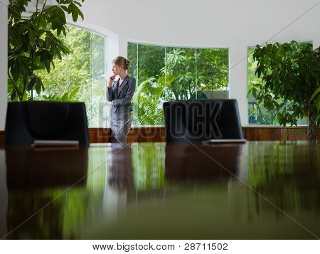 Businesswoman Contemplating Out Of Window In Meeting Room