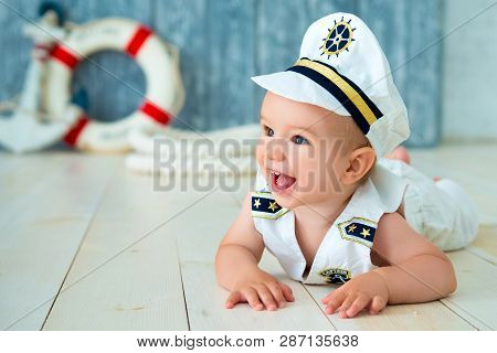 Photoshoot For A Boy Of One Year. Little Sea Captain, Sailor On Toy Ship With Steering Wheel. Sea An