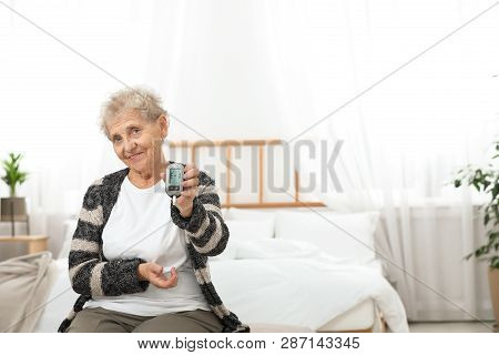 Senior Woman Holding Digital Glucose Meter At Home. Diabetes Control