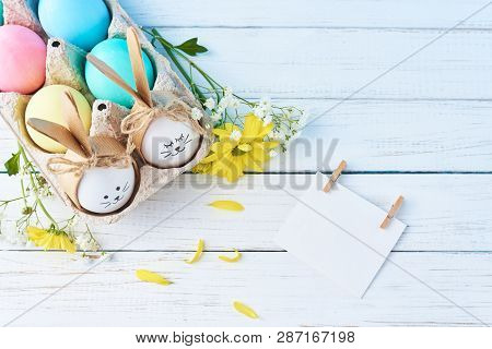 Easter Colored Eggs With Painted Faces In Paper Tray With Decorationd On White Background