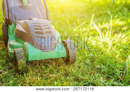 Lawn Mower Cutting Green Grass In Backyard In Sunny Day. Gardening Country Lifestyle Background. Bea