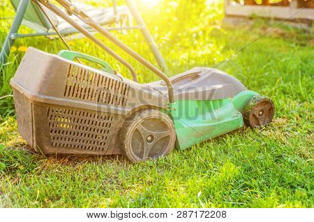 Lawn Mower Cutting Green Grass In Backyard In Sunny Day. Gardening Country Lifestyle Background. Bea