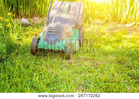 Lawn Mower Cutting Green Grass In Backyard In Sunny Day. Gardening Country Lifestyle Background. Bea