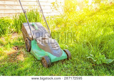 Lawn Mower Cutting Green Grass In Backyard In Sunny Day. Gardening Country Lifestyle Background. Bea