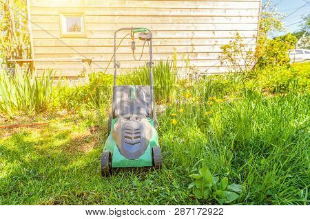 Lawn Mower Cutting Green Grass In Backyard In Sunny Day. Gardening Country Lifestyle Background. Bea