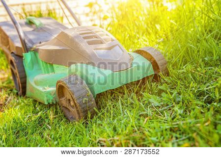 Lawn Mower Cutting Green Grass In Backyard In Sunny Day. Gardening Country Lifestyle Background. Bea