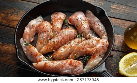 Raw Chicken Breast Mini Fillets In Rastic Cast Iron Skillet, Frying Pan With Herbs And Sea Salt