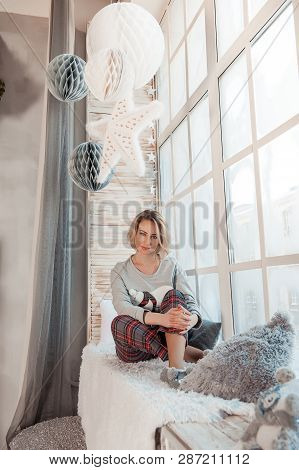 Beautiful Girl Sitting Near A Large Window.