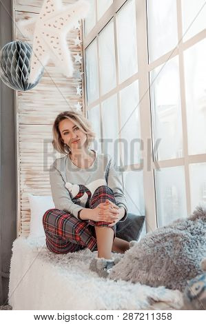 Beautiful Girl Sitting Near A Large Window.