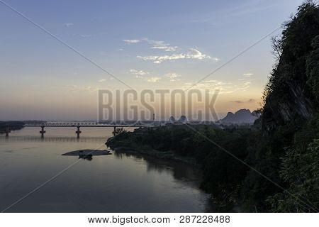 Wide Angle Picture Of Bat Cave And Thanlwin Bridge Over The River During Sunset Time, Located In Hpa