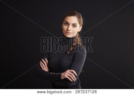 Attractive Young Woman Studio Portrait While Standing At Dark Background