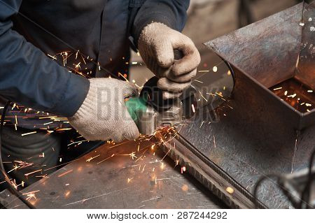 Blacksmith Grindering A Metal Plate Holding An Angle Grinder Shot From Above. The Blacksmith Work Cl