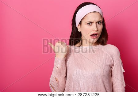 Girl Asks What Happened While Showing Something Aside. Atonished Woman Points Left With Thumb Finger