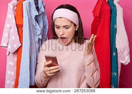 Shocked Woman Looks At Smartphone Display. Interesting Information On Screen. Dark Haired Lady Raise