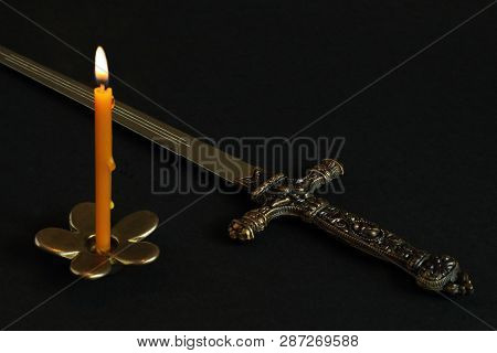 Burning Wax Candle On Bronze Candlestick In Shape Of Flower And Dagger-stylet (replica) With Bronze 