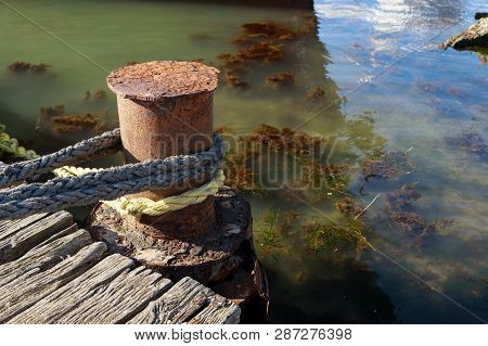 Rope Is Tied To An Old Rusty Pillar Of A Dilapidated Wooden Jetty
