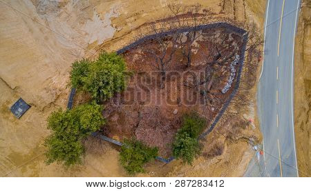 Aerial View Of Small Grove Of Trees At Construction Site Fenced Off For Preservation.