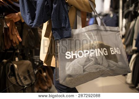 Young woman shopping in a fashion store, trying on some clothes she likes (color toned image; shallow DOF)