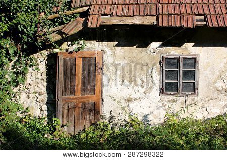 Wooden Doors And Windows Mounted With Decorative Rusted Metal Hinges On Dilapidated Wall Of Small Ab