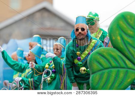 New Orleans, Louisiana, USA - February 23, 2019: Mardi Gras Parade, Men and women on top of a float using face masks and giving away beads to the spectators