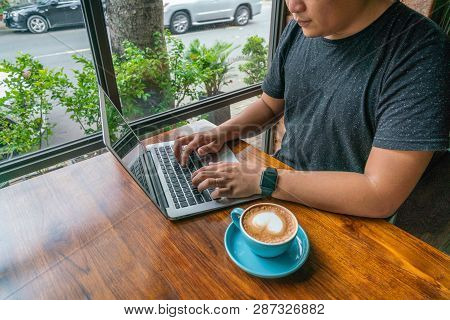 Young Man Working On Laptop With The Cup Of Coffed