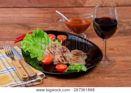 Grilled Sappy Pork Neck Steaks With Lettuce Leaves And Cherry Tomatoes On Black Dish, Glass Of Red W
