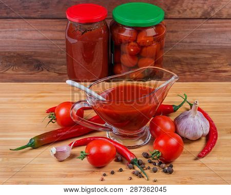 Tomato Sauce In The Glass Gravy Boat Next To Several Raw Ingredients For Its Preparation Against Of 