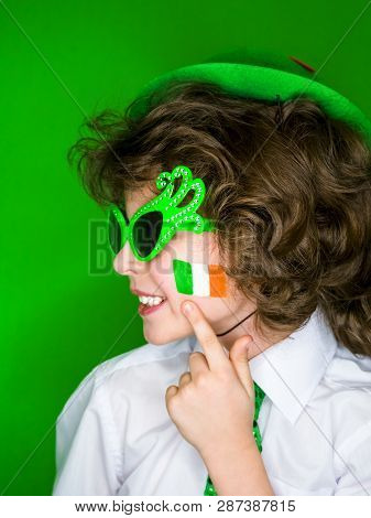 Child Celebrating St. Patricks Day Showing His Make-up. A Small, Curly Boy In Green Carnival Accesso