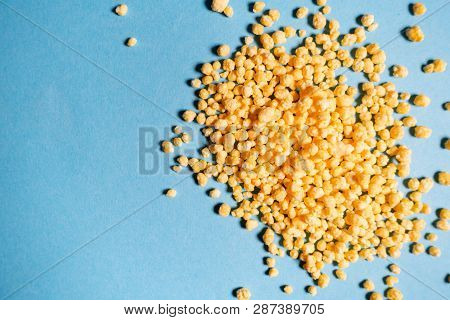Yellow Granules On A Blue Background. Candies