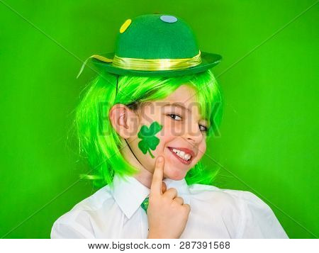 Child Celebrating St. Patricks Day Showing His Make-up. A Small, Boy In Green Carnival Wig Points Hi