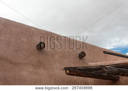 Exterior Red Adobe Building With Beams, Cloudy Sky, Horizontal Aspect