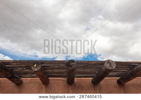 Wide View Detail Of Red Adobe Exterior With Beans, Wood Slats, Blue Sky With Clouds, Horizontal Aspe