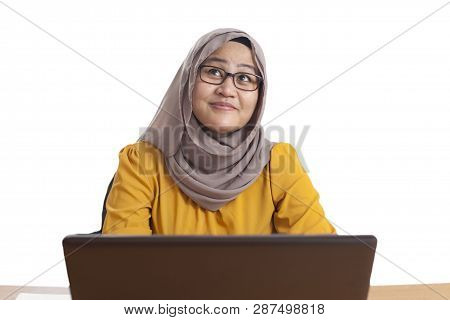 Muslim Businesswoman Working On Laptop At The Office, Thinking Gesture