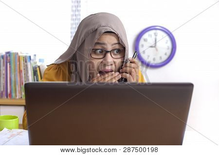 Portrait Of Asian Muslim Businesswoman Is Secretly Talking On The Phone At Work. Leaking Confidentia