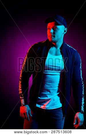 Portrait Of A Young Happy Serious Man In Cap, White Shirt, Bomber At Studio. High Fashion Male Model