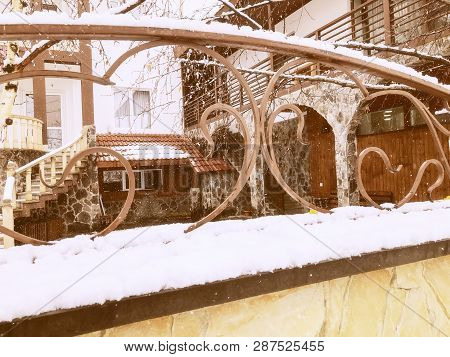 Srone Gate With Decorative Steel Trim. Snowfall On The Street.noon.