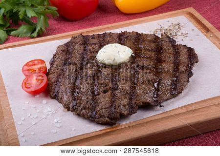 Prepared Steak Served With Butter On Wooden Board
