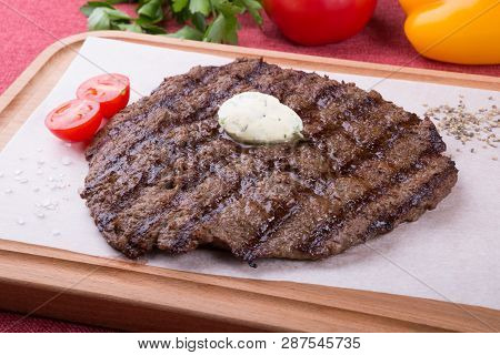 Prepared Steak Served With Butter On Wooden Board
