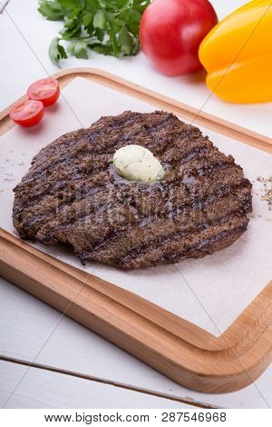 Prepared Steak Served With Butter On Wooden Board