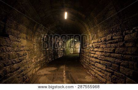 Tunnel Entrance In The Forest. Walls Made Of Rocks