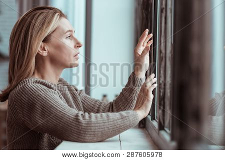Concerned Woman Standing Near Window Feeling Depressed