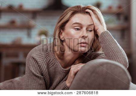 Dark-eyed Woman Wearing Brown Sweater Sitting On The Sofa