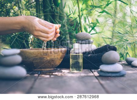 Spa Background With Woman's Hands And Clear Water On An Old Wooden Table. Japanese Style. Simplicity