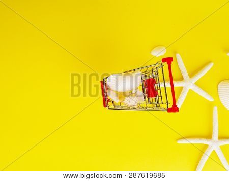 Shopping Cart , Troley With Seashells On Yellow Background.