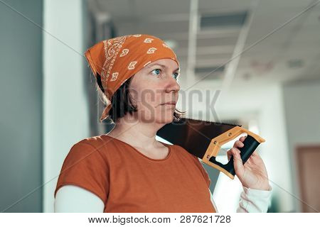 Self Employed Female Carpenter With Crosscut Hand Saw In Her Small Business Woodwork Workshop