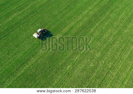 Unrecognizable Farmer In Agricultural Tractor Is Fertlizing Wheat Crop Field With Npk Fertilizers, A