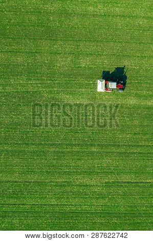 Agricultural Tractor Is Fertlizing Wheat Crop Field With Npk Fertilizers, Aerial View From Drone Pov