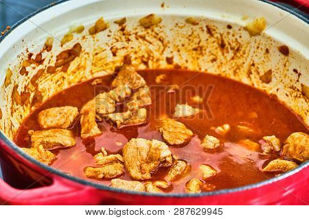 Preparing Perkelt Sauce - Cooking Meat, Dried Pepper, Liquid And Onion In Red Pot